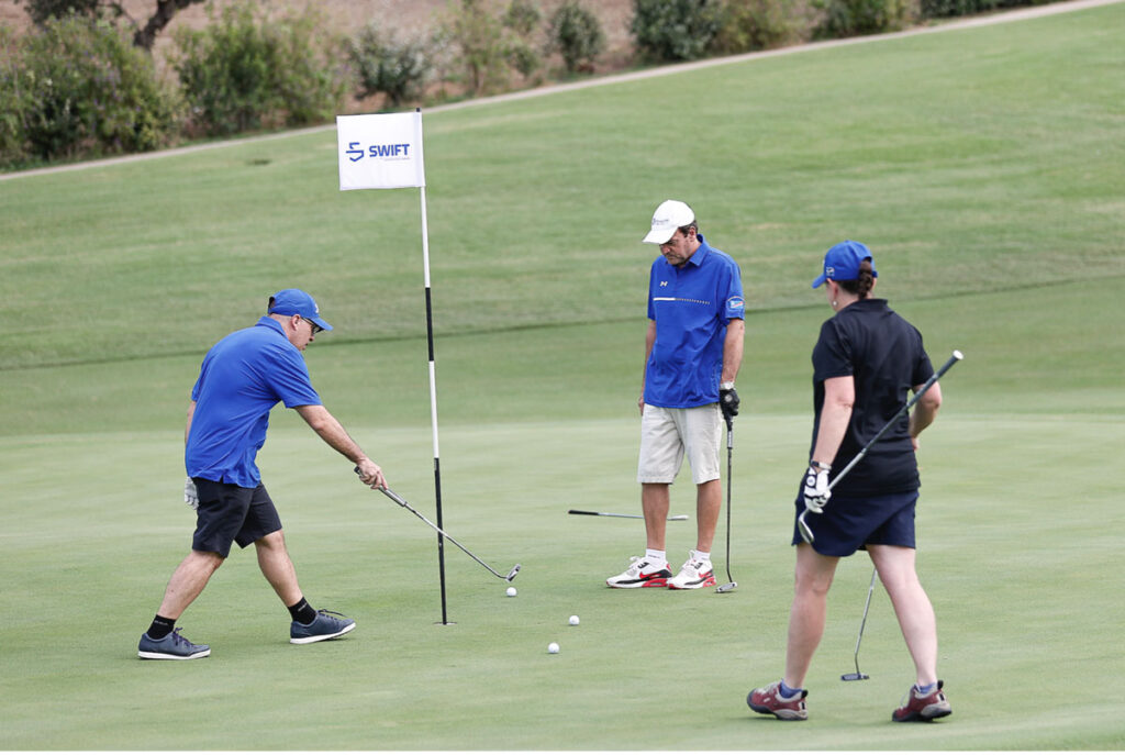 Golfers at a flag, golfing.