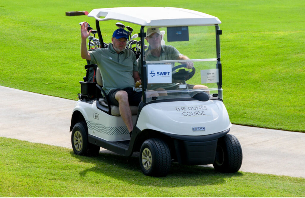 Two Swift Marine employees in a golf cart at a golf course.